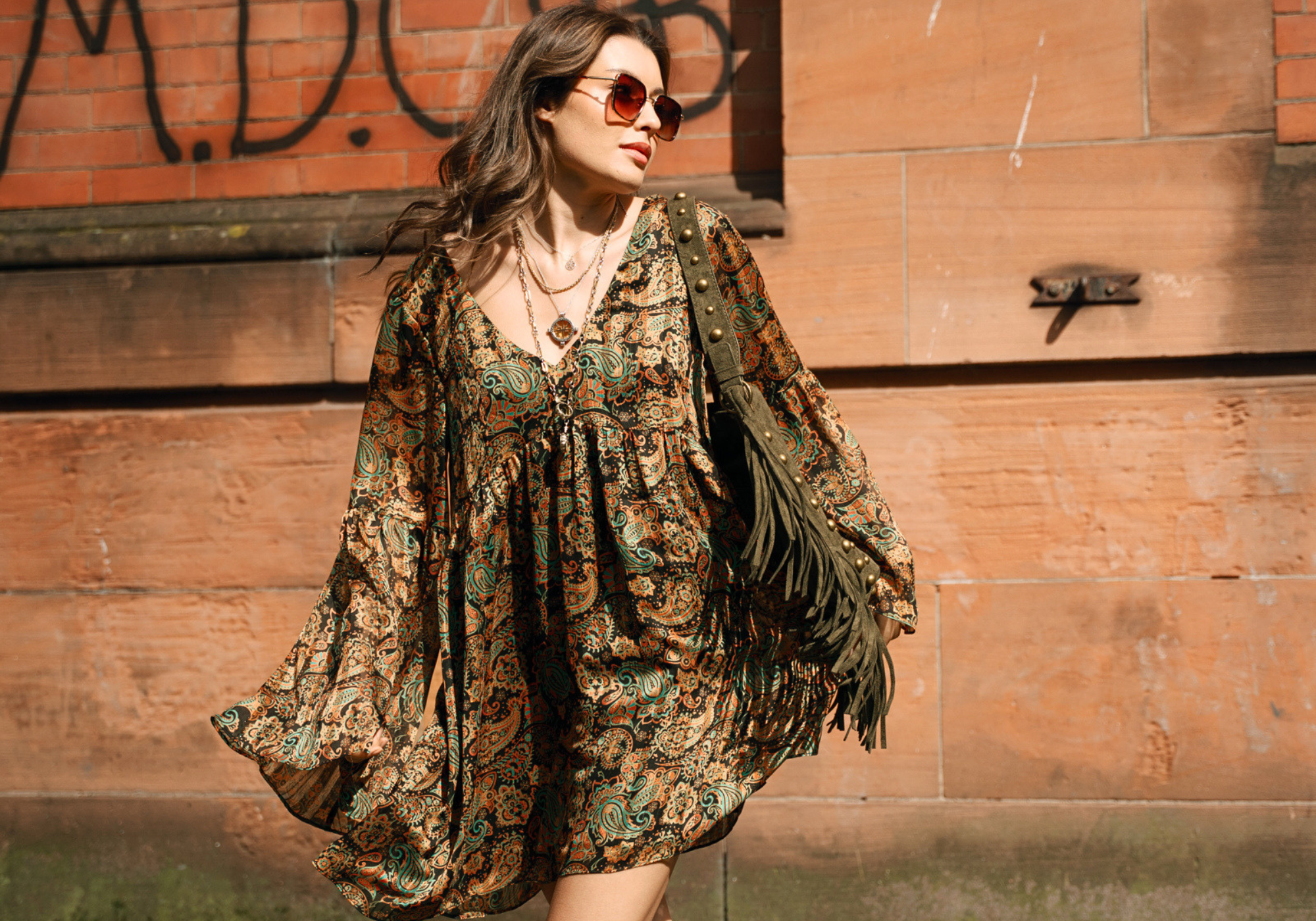 Model wearing Little Lies Ringo paisley smock dress styled with Willow khaki fringe suede bag and Cher sunglasses for relaxed boho-inspired street style